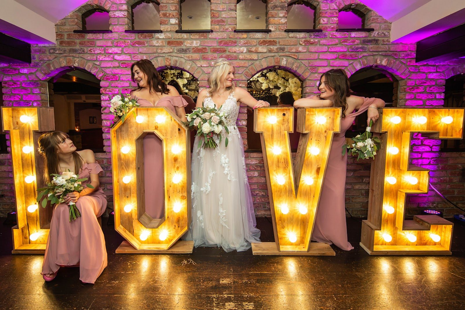 The bride and her bridesmaids in front of the illuminated LOVE letters