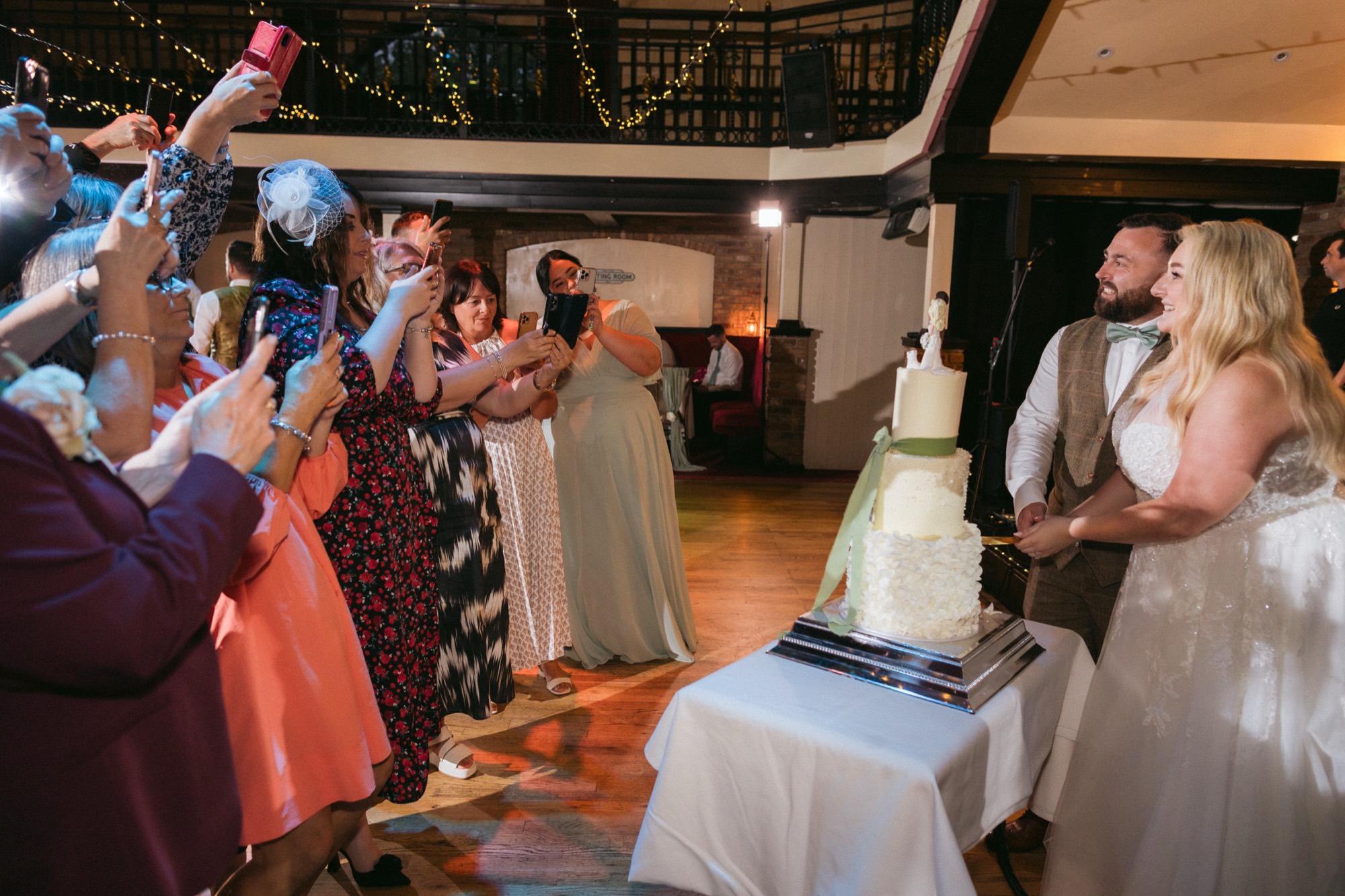 Guests cheering as the couple cut their cake