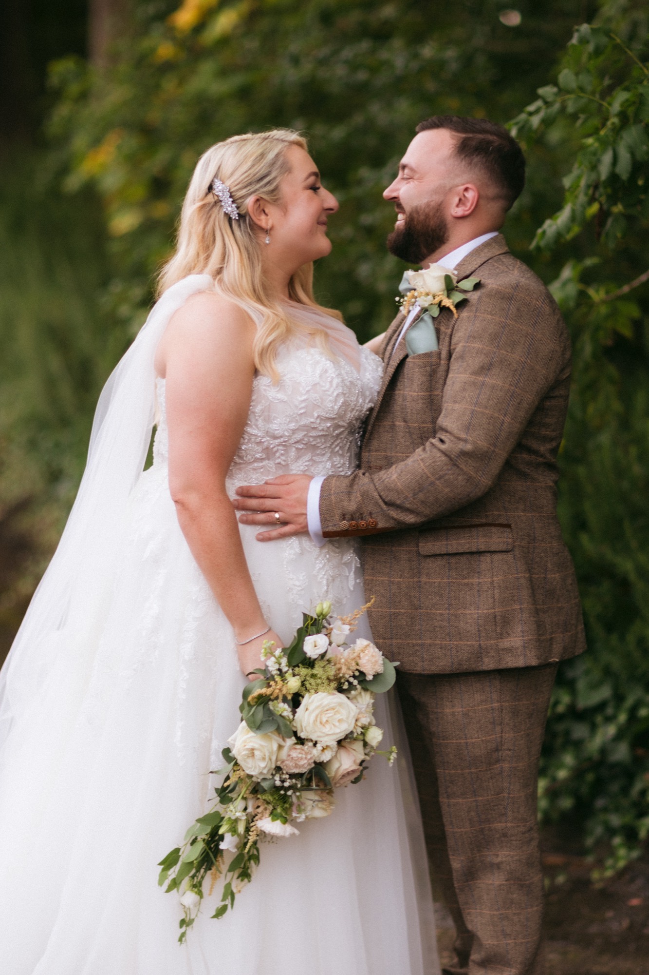 A couple outside the venue, the bride holding a bouquet