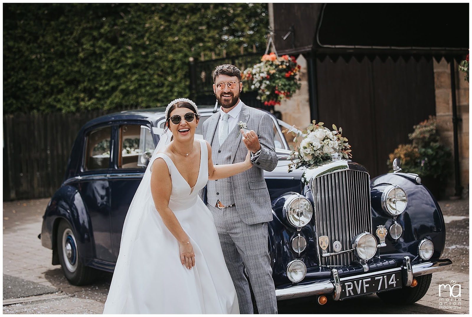 A couple beside their vintage wedding car outside the venue