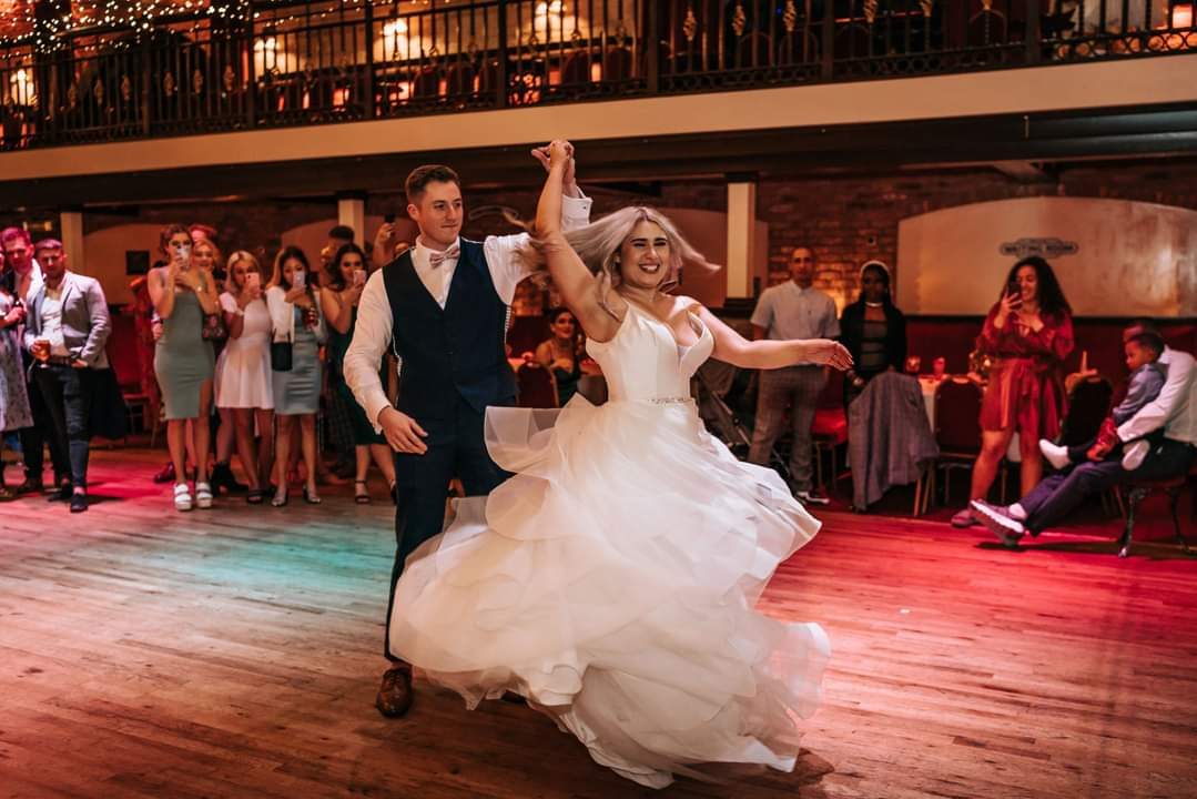 A couple spinning on the dance floor while their guests watch