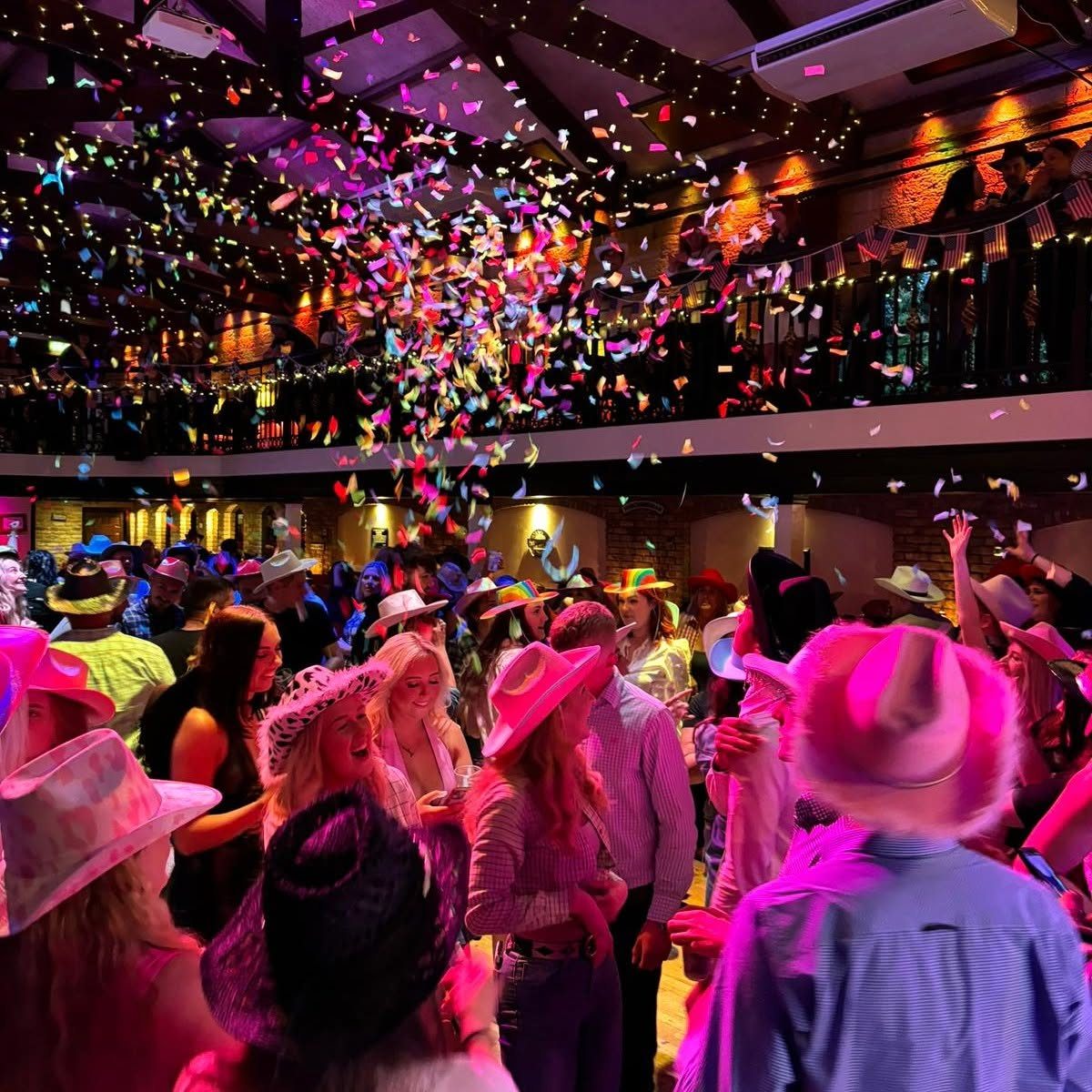A crowd in fancy dress under confetti at an evening party
