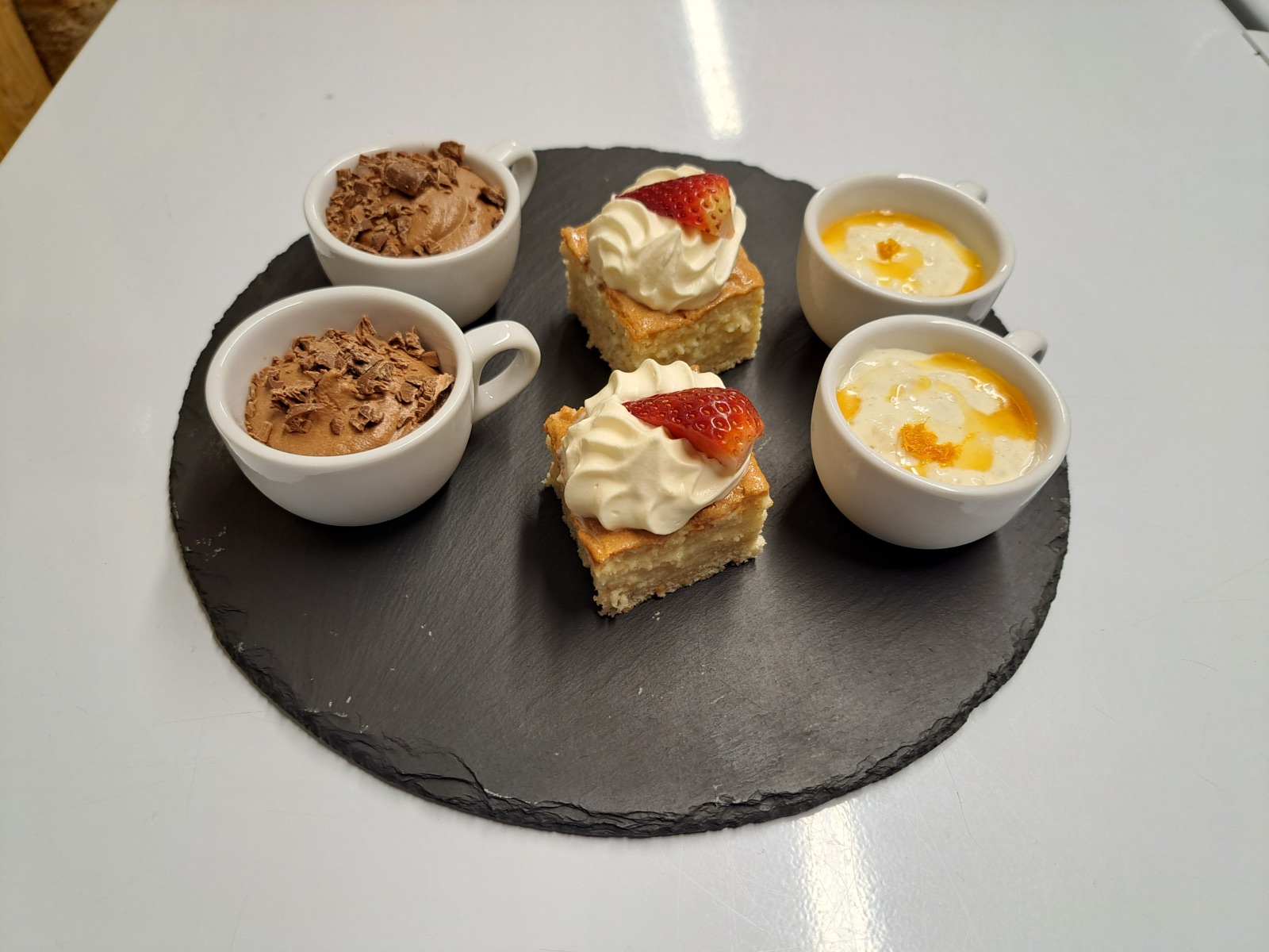 A dessert sharing platter of chocolate mousse, vanilla slice and posset on slate