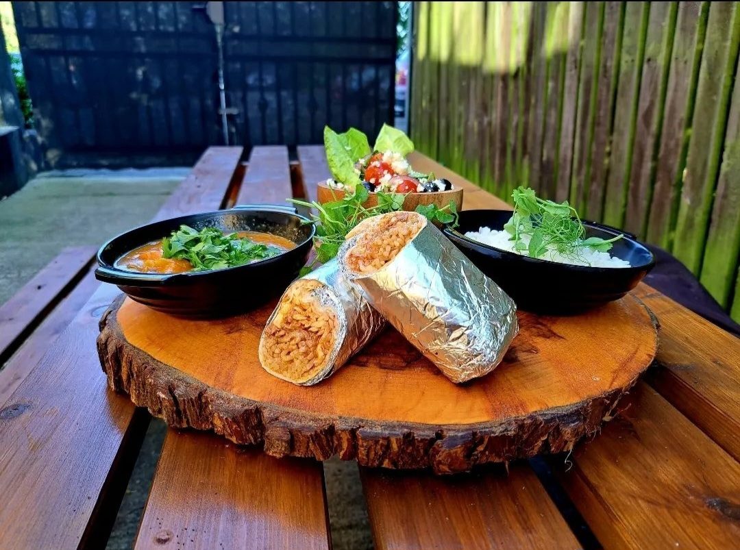 Street food wraps and sharing bowls on a wooden board outside