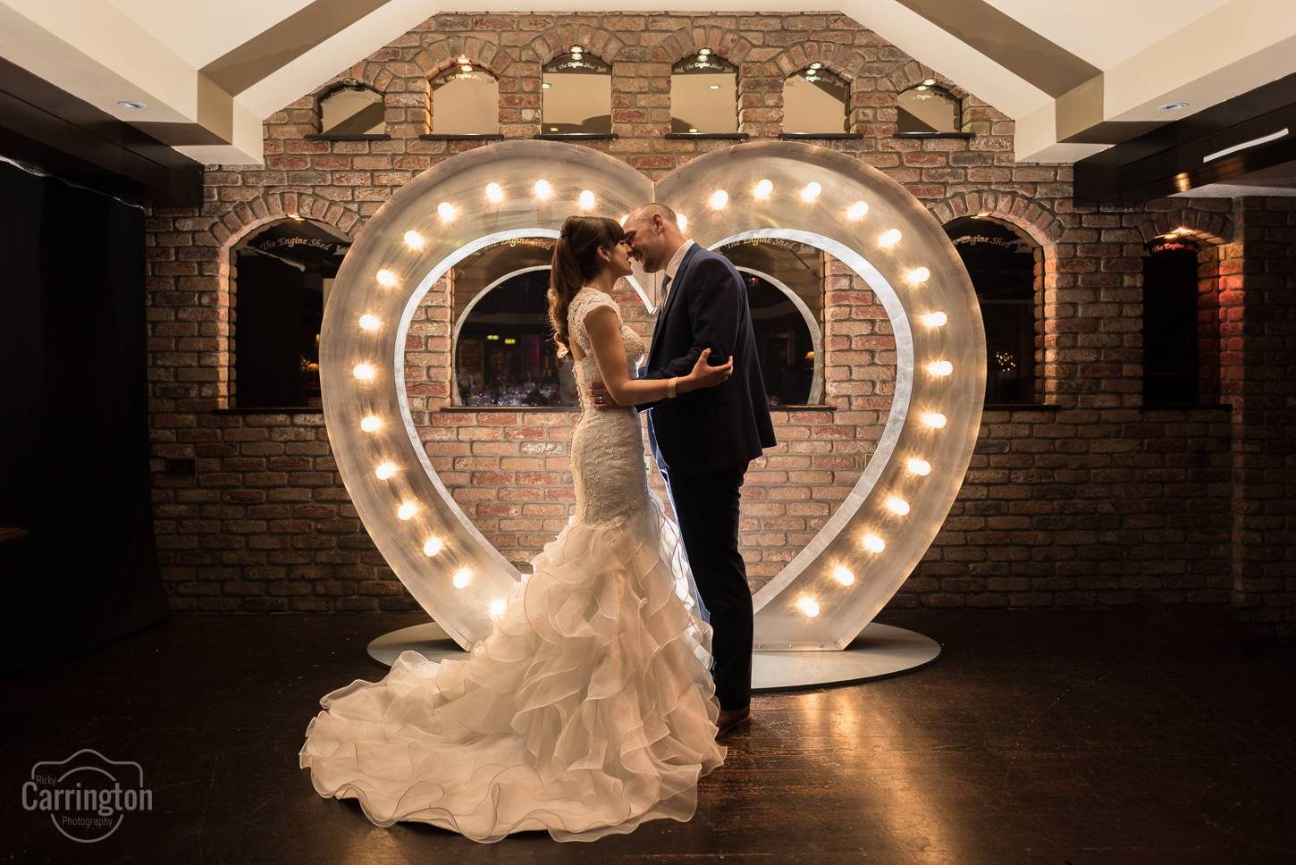 A couple together inside a giant illuminated heart