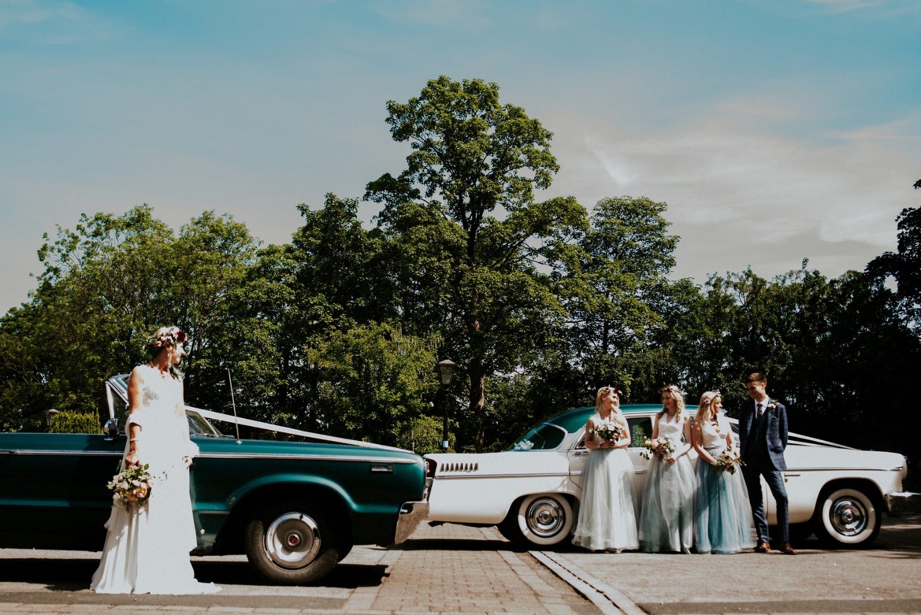 A couple and their guests outside the venue with the wedding cars