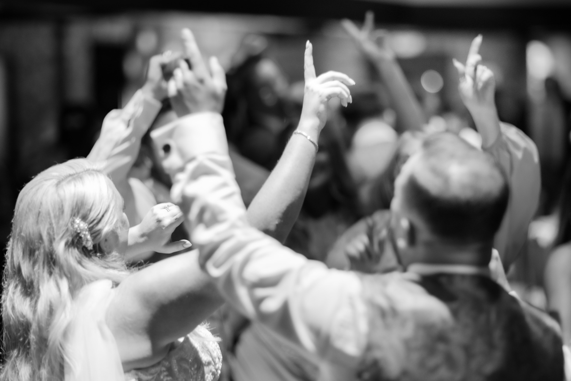 Guests dancing with their hands in the air, in black and white