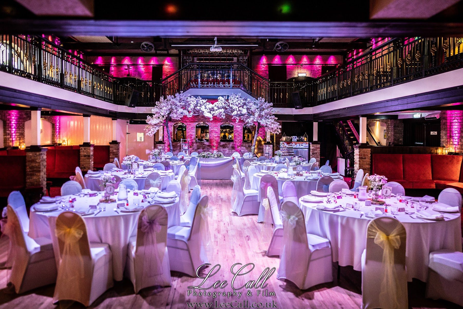 The main hall dressed with round tables and lit in deep pink