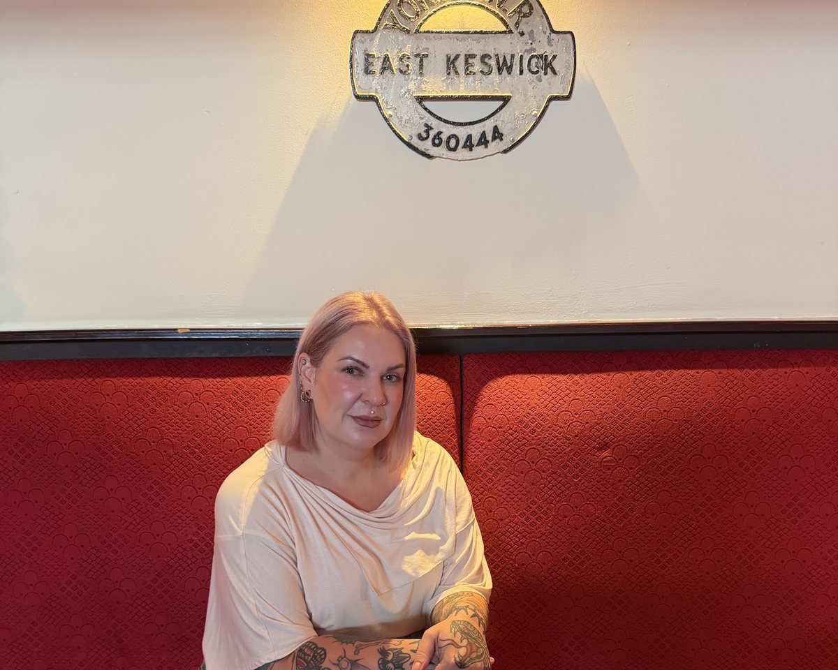 Jen, the sous chef, sitting beneath the East Keswick railway sign