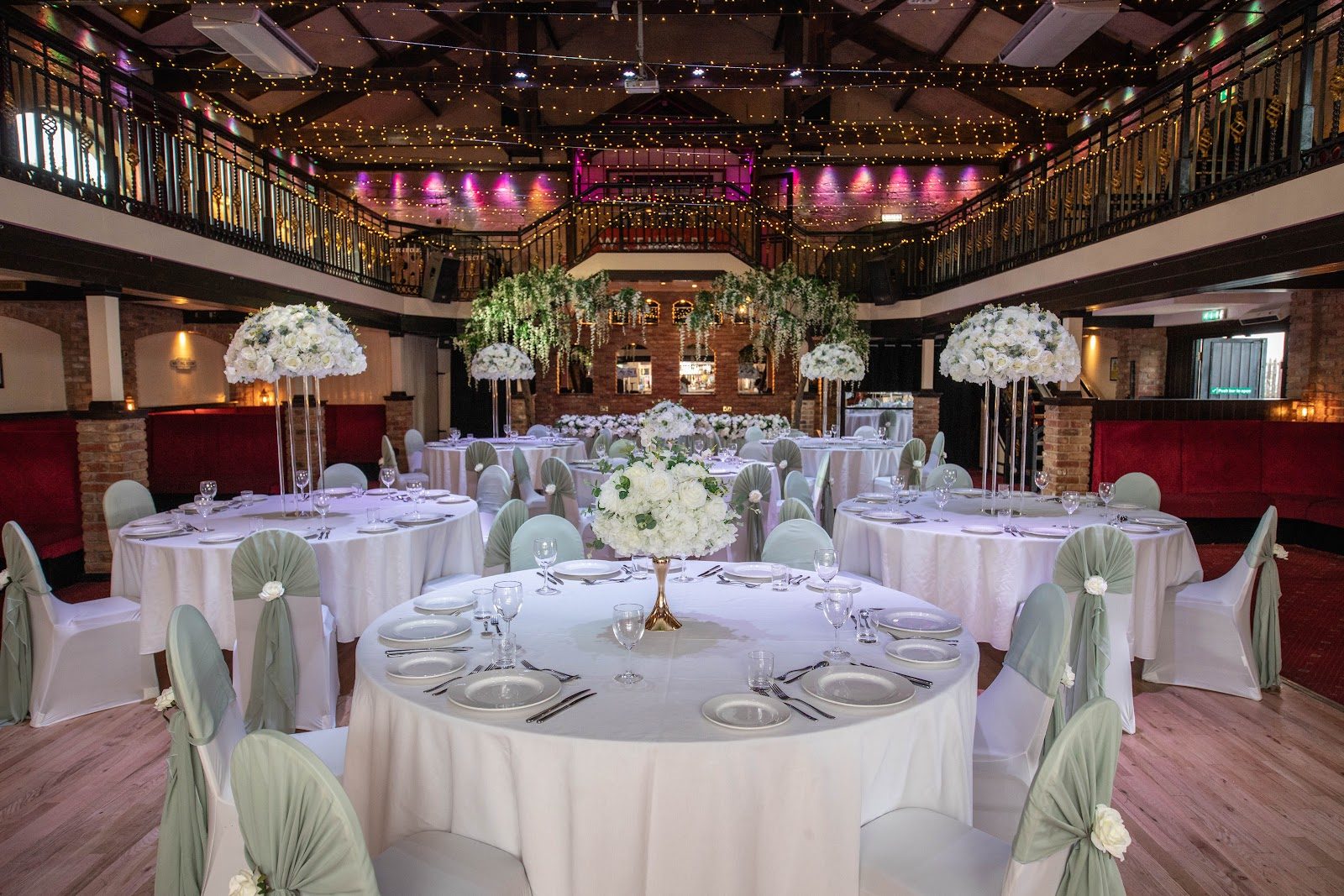 The main hall dressed with round tables, florals and hanging pom-poms