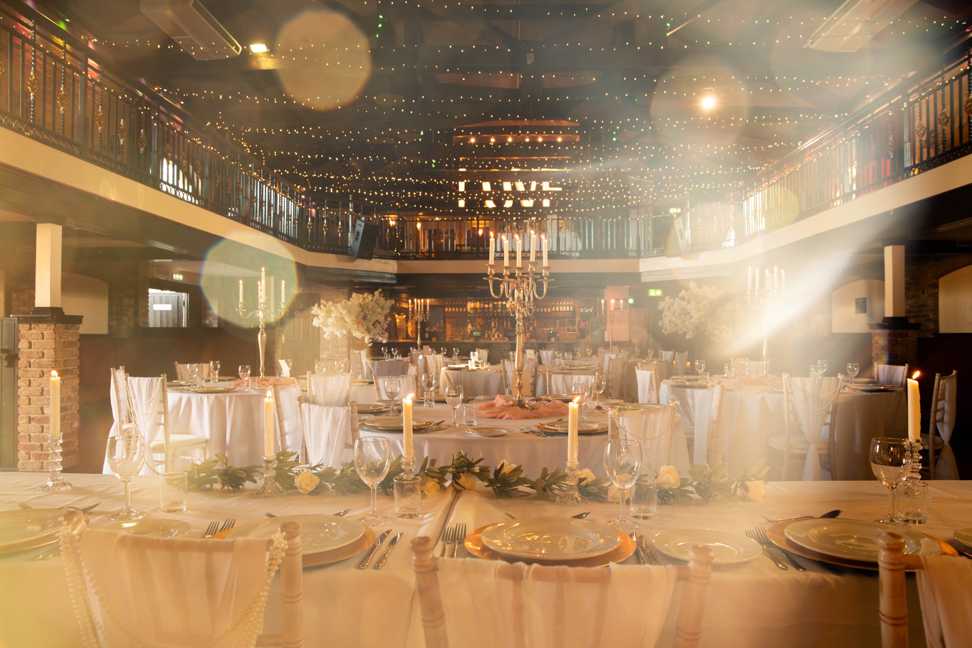 The main hall dressed for a wedding breakfast, candlelit with festoon lights above